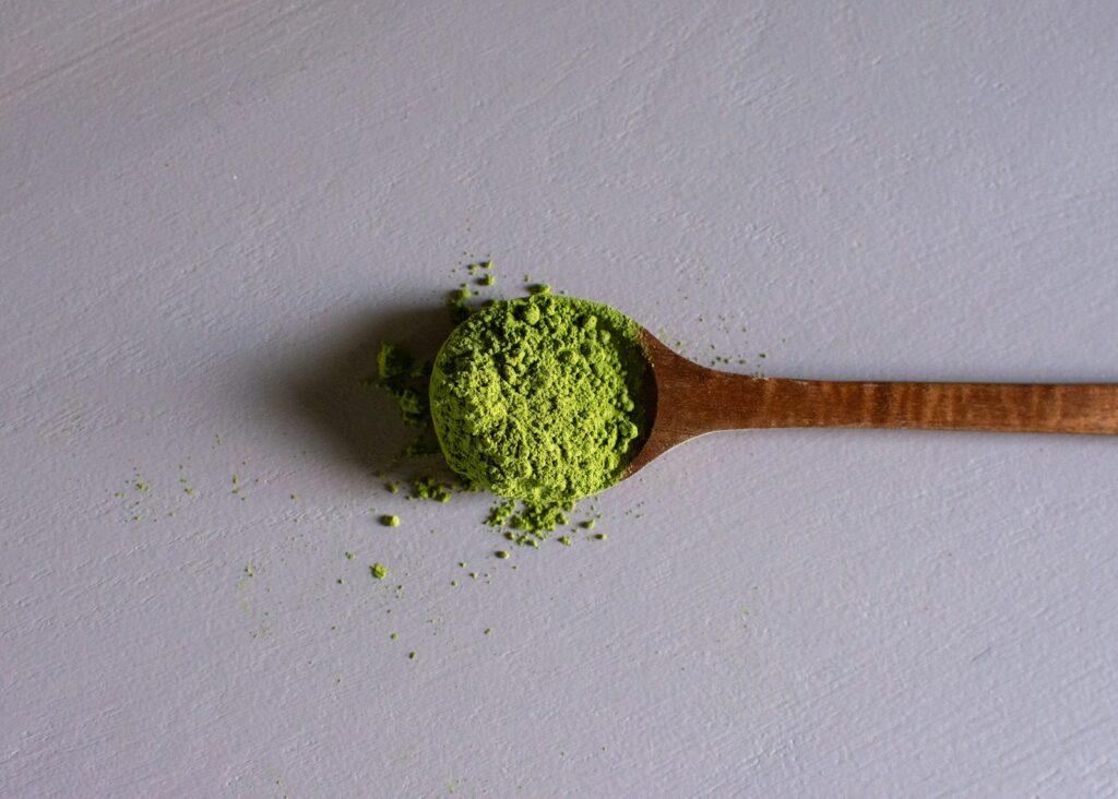 a wooden spoon filled with green powder