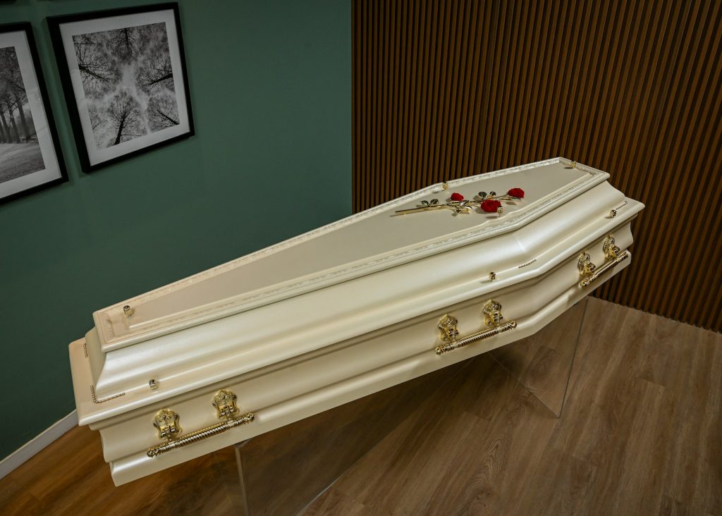 A white casket sitting on top of a hard wood floor